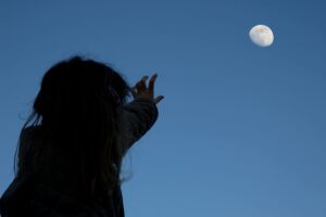 A child stretching his hand towards the moon