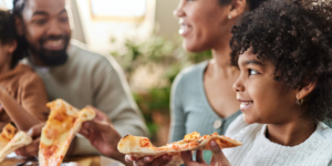 A family eating pizza and smiling together