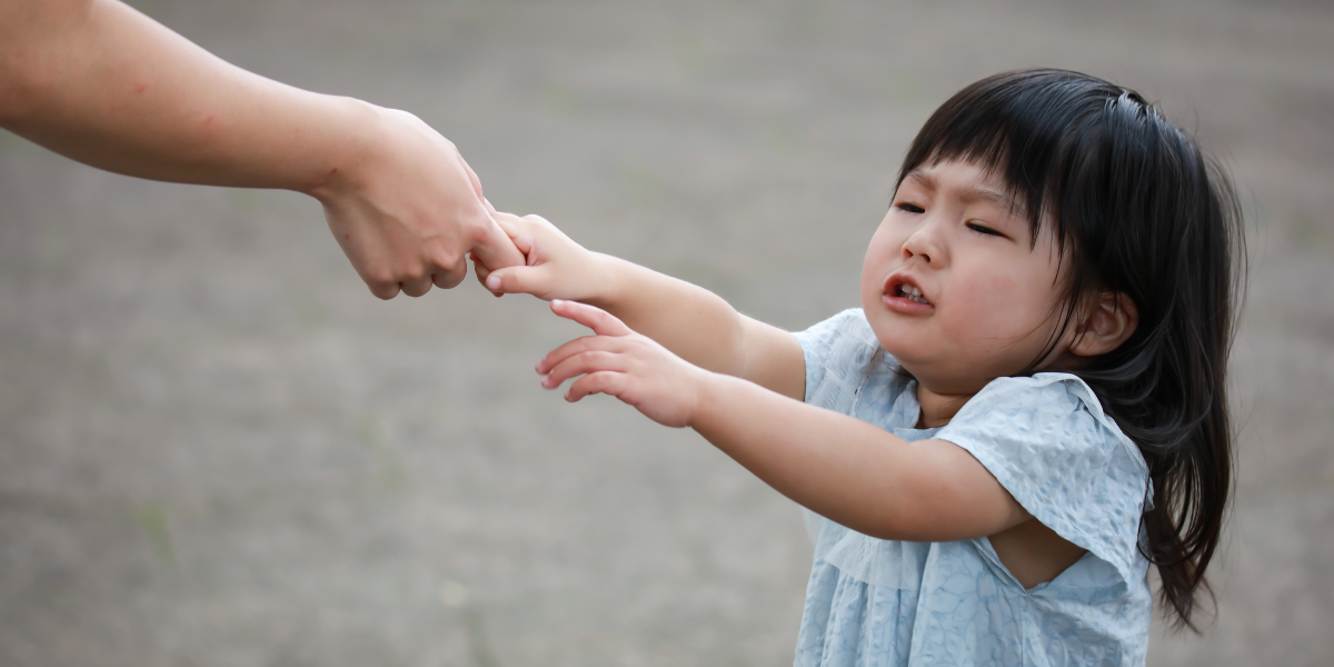 A little girl grabbing mom's finger