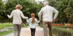 A little redheaded girl holding hands and walking in the middle of her grandparents