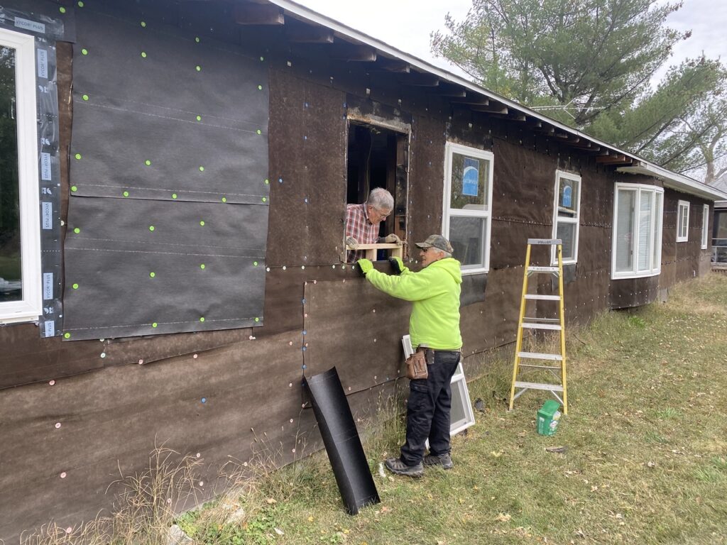 A couple of men repairing a house that was damaged.