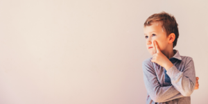 A little boy tapping his chin thoughtfully